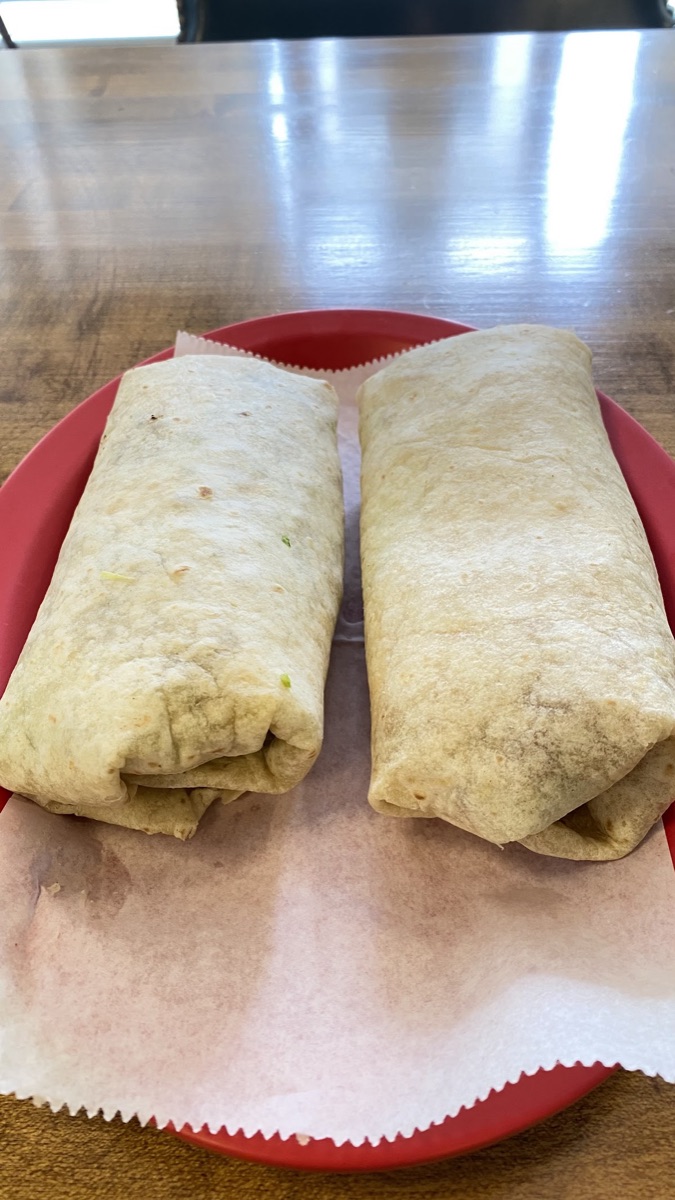 Two hearty stuffed burritos on a red plate